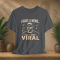 Gray t-shirt with graphic design and text on a wooden surface with plants and a textured wall background