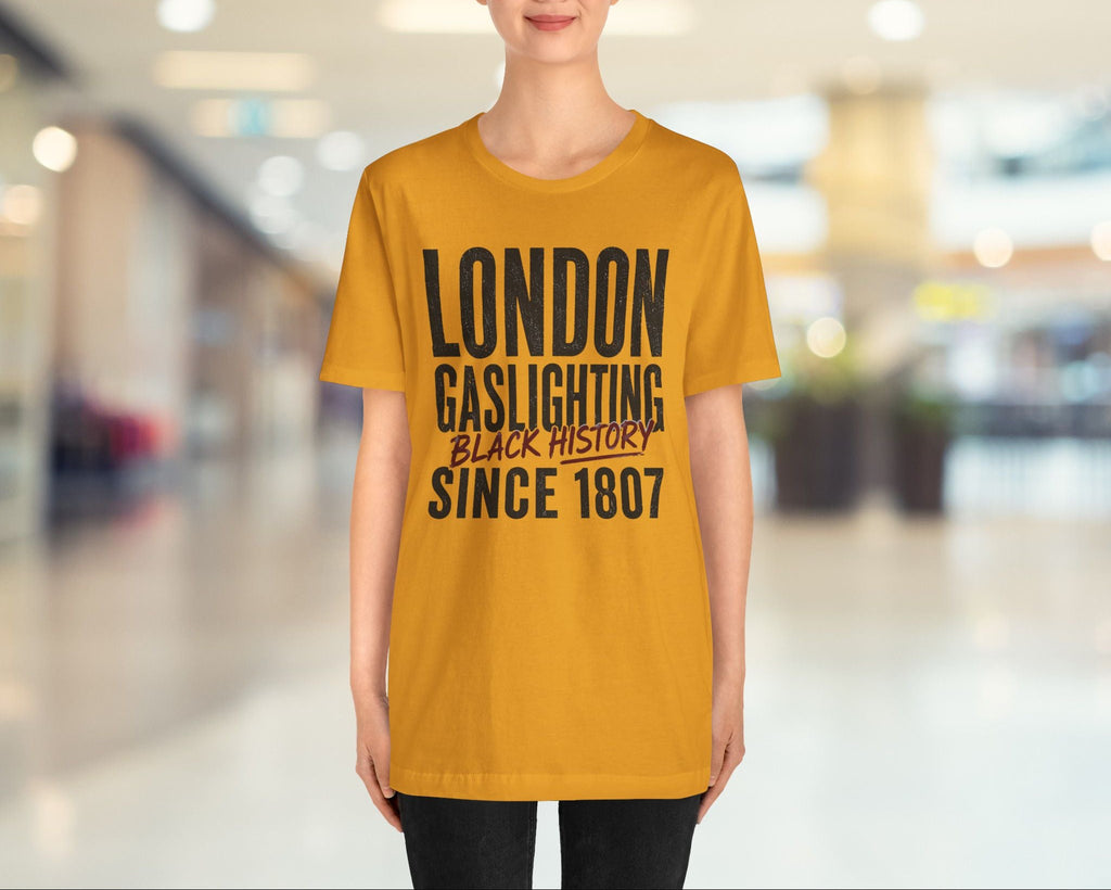 Person wearing a mustard yellow t-shirt with text in an indoor setting