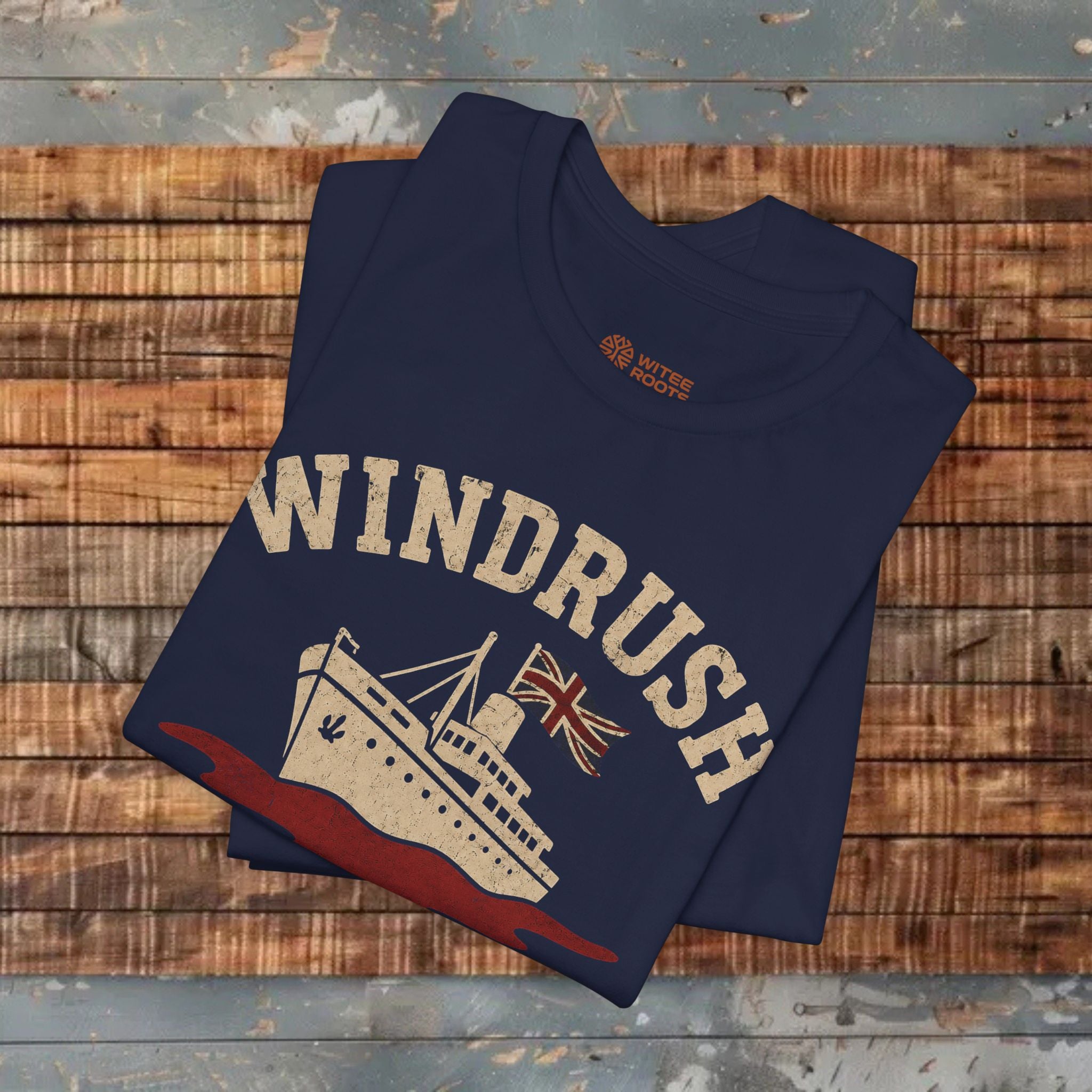 Folded navy blue t-shirt with 'Windrush' design on a wooden surface