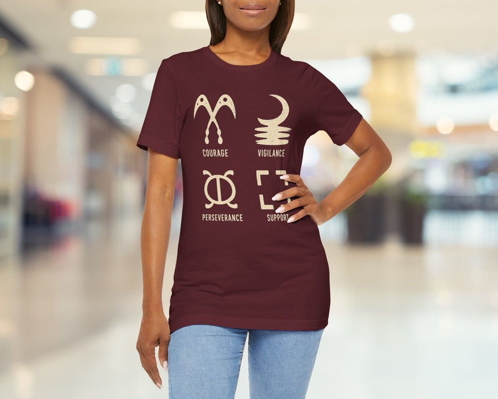 Person wearing a maroon t-shirt with white graphics and text in a blurred indoor setting