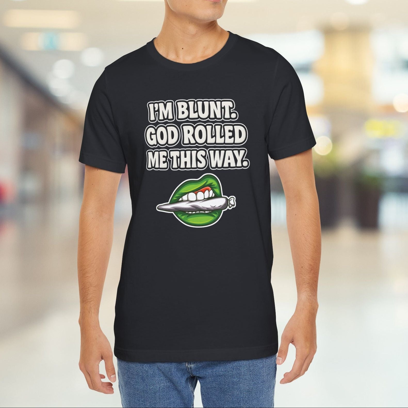 Person wearing a black t-shirt with graphic design and text in a blurred indoor setting