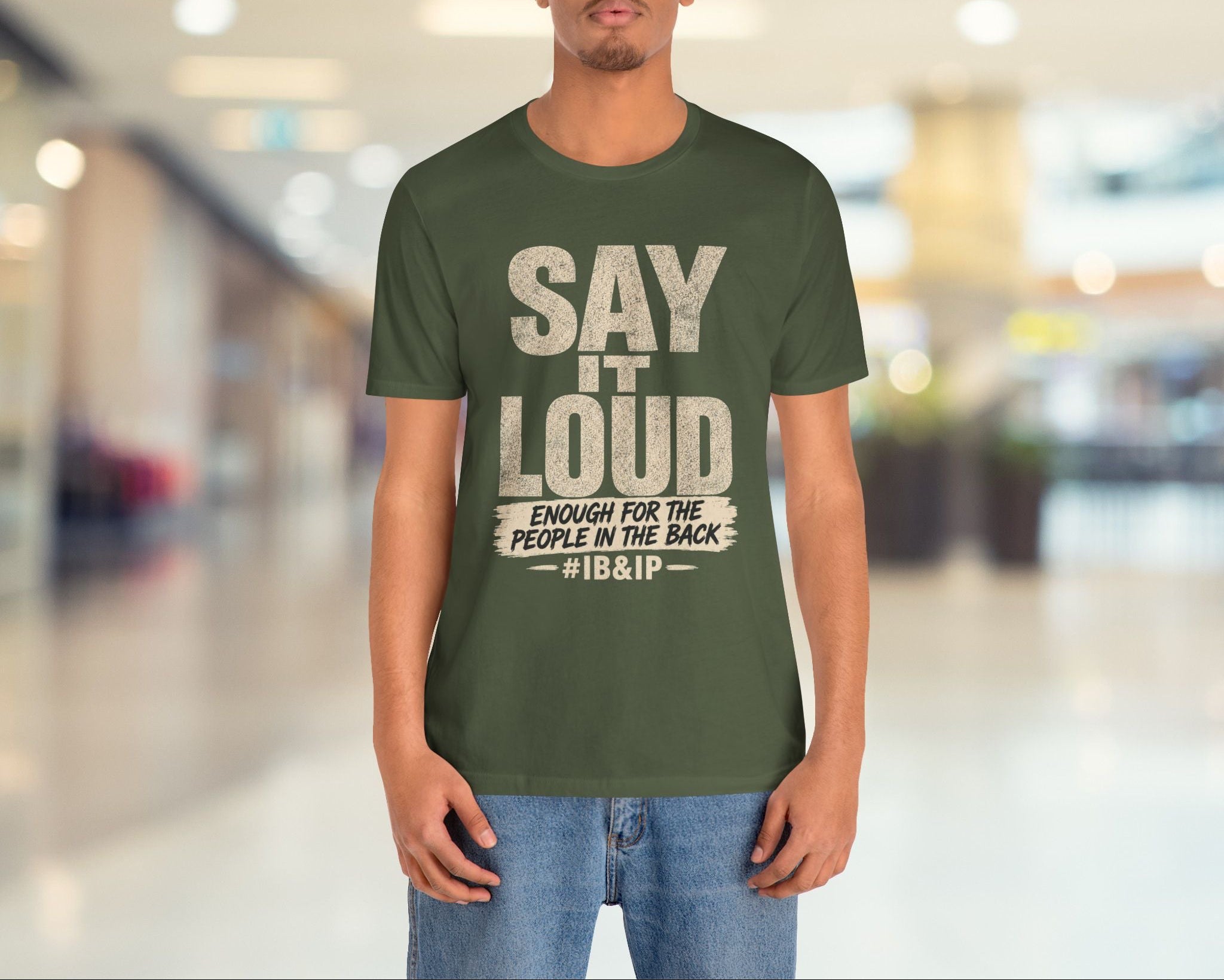Person wearing a green t-shirt with text in a blurred indoor setting
