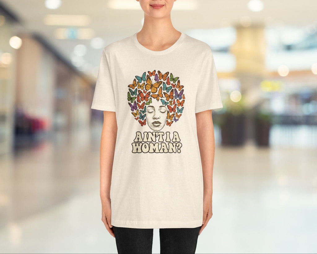 Person wearing a white t-shirt with a colorful design and text in an indoor setting