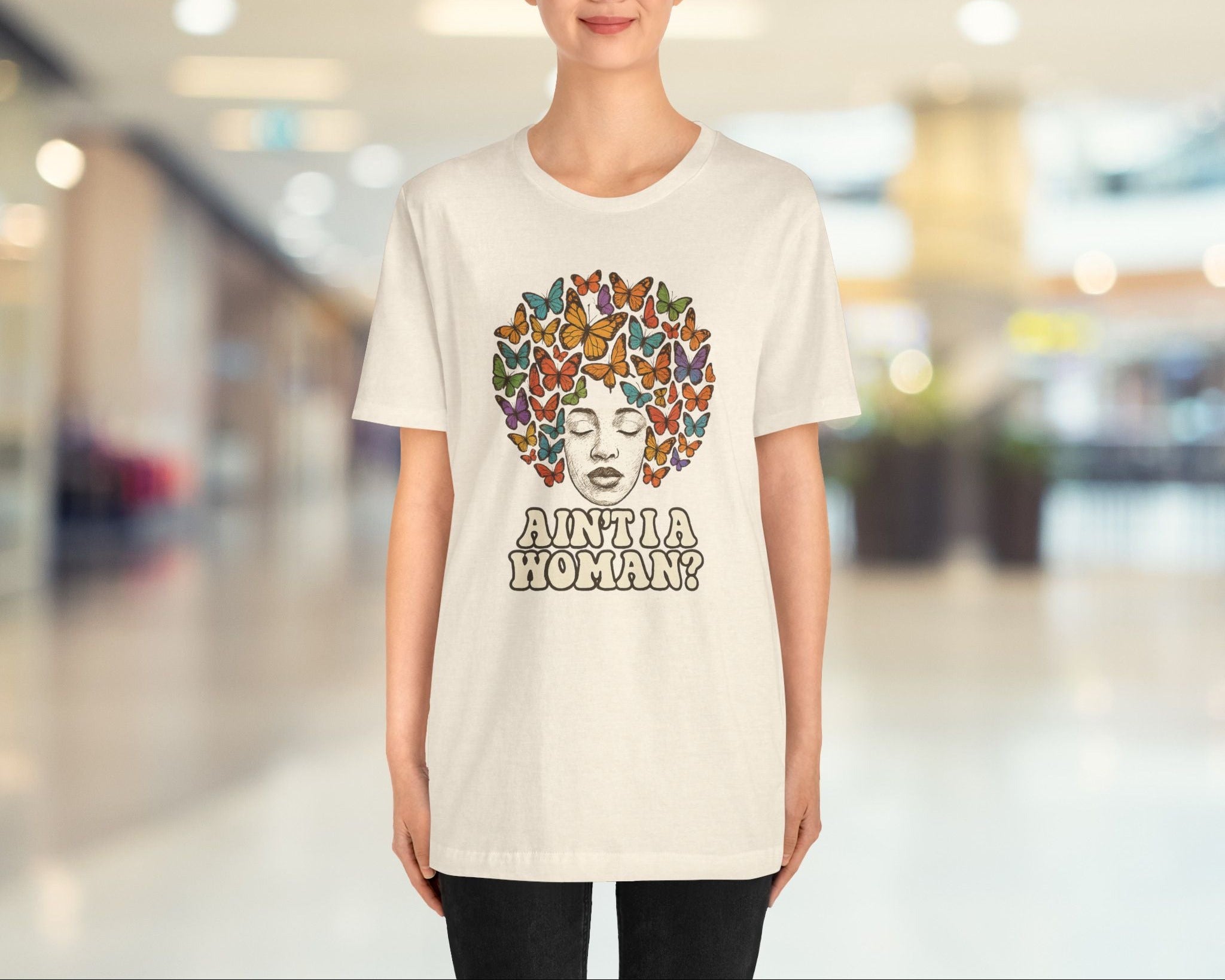 Person wearing a white t-shirt with a colorful design and text in an indoor setting
