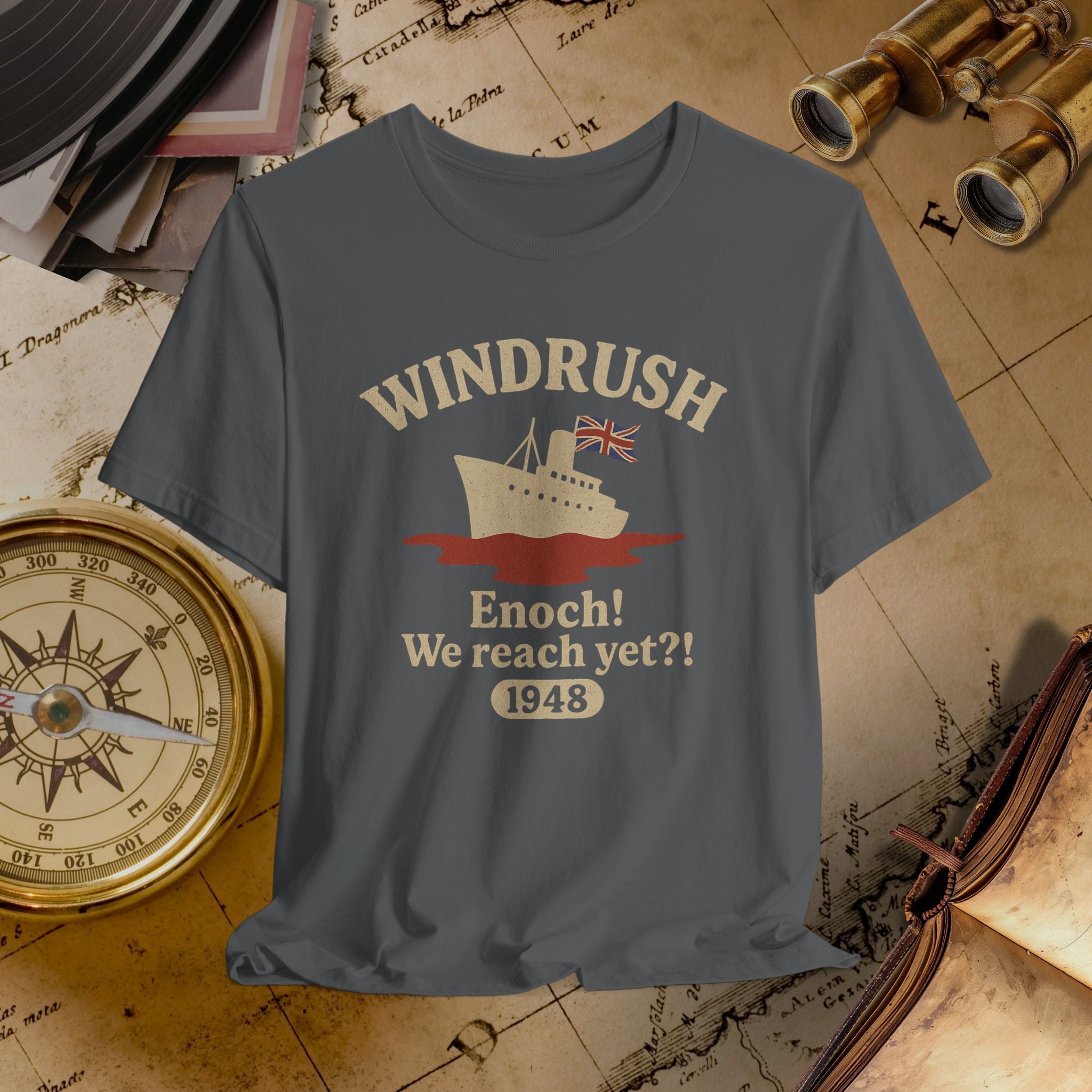 Gray t-shirt with 'Windrush' design featuring a ship and British flag on a vintage map background.