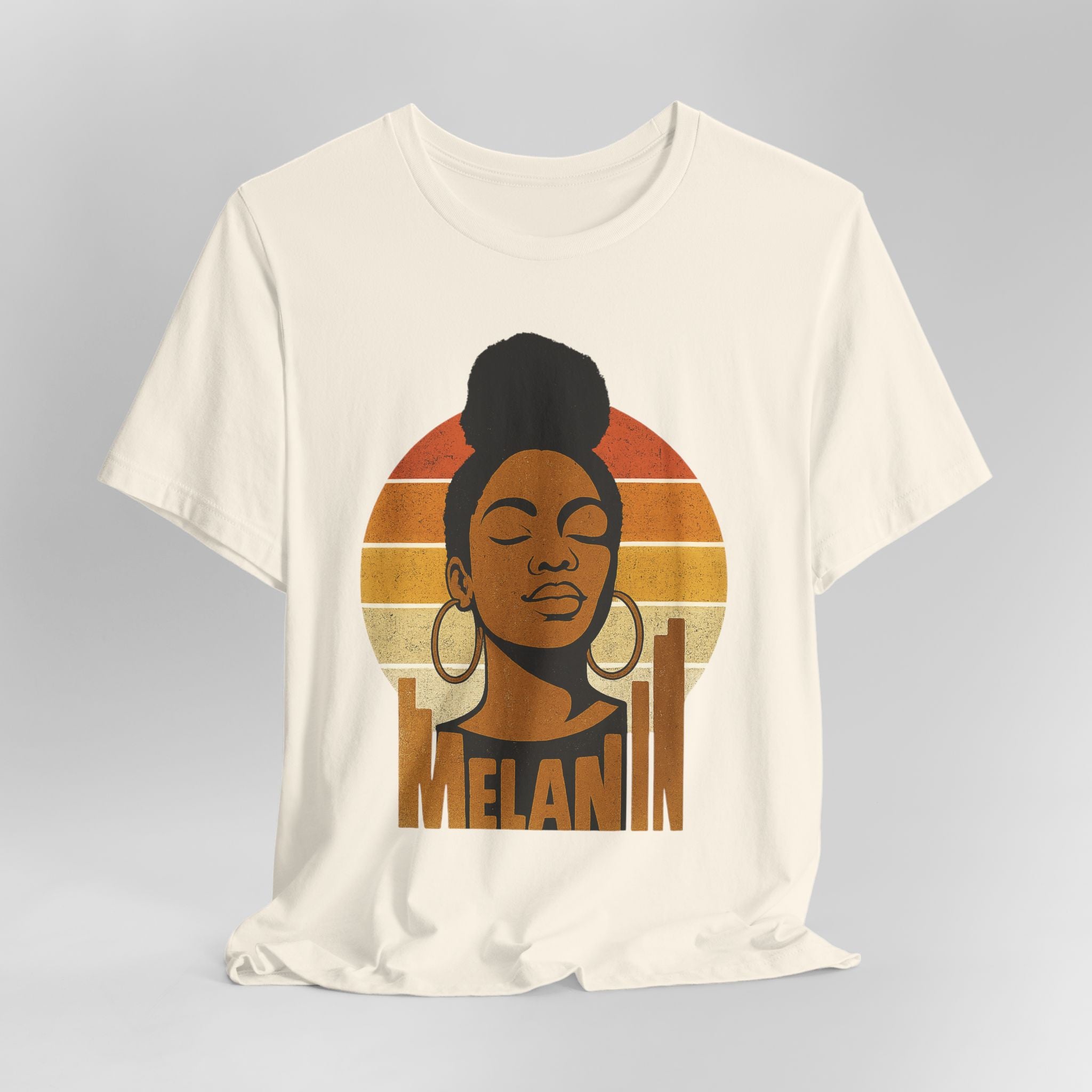Cream t-shirt with a graphic of a woman's face and 'Melanin' text on a gray background