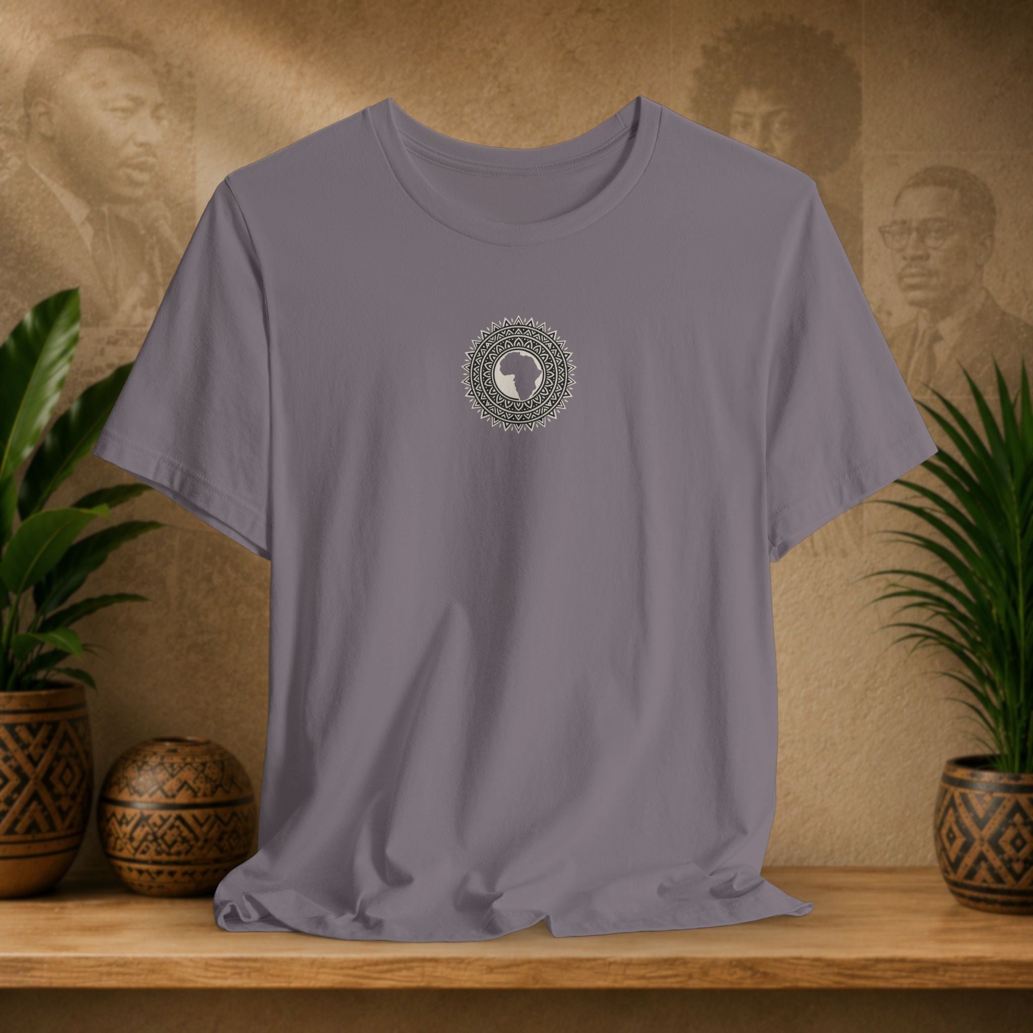 Gray t-shirt with a circular design on a wooden surface with plants and decorative items.