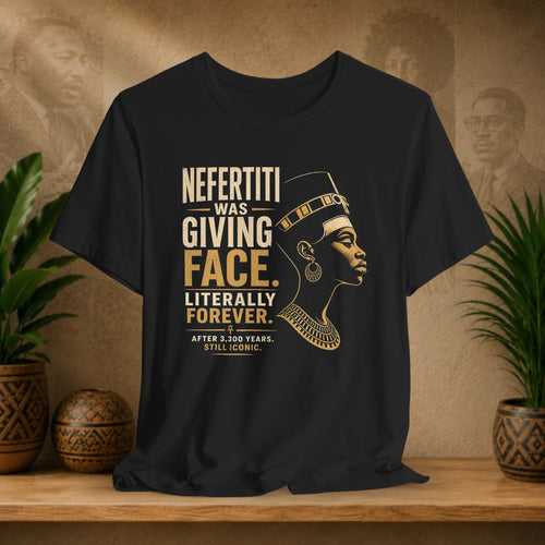 Black t-shirt with gold text and graphic of a historical figure on a wooden surface with plants and decorative items.