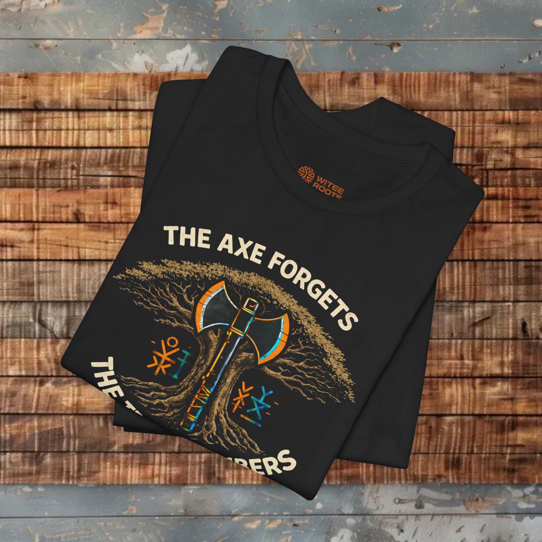 Folded black t-shirt with graphic design and text on a wooden surface