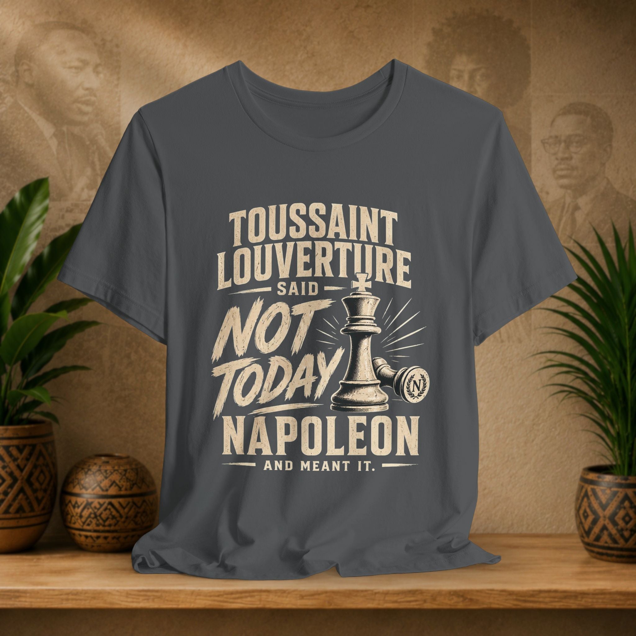 Gray t-shirt with historical quote graphic on a wooden surface with plants