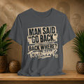 Gray t-shirt with humorous text design on a wooden surface with plants and a decorative wall.