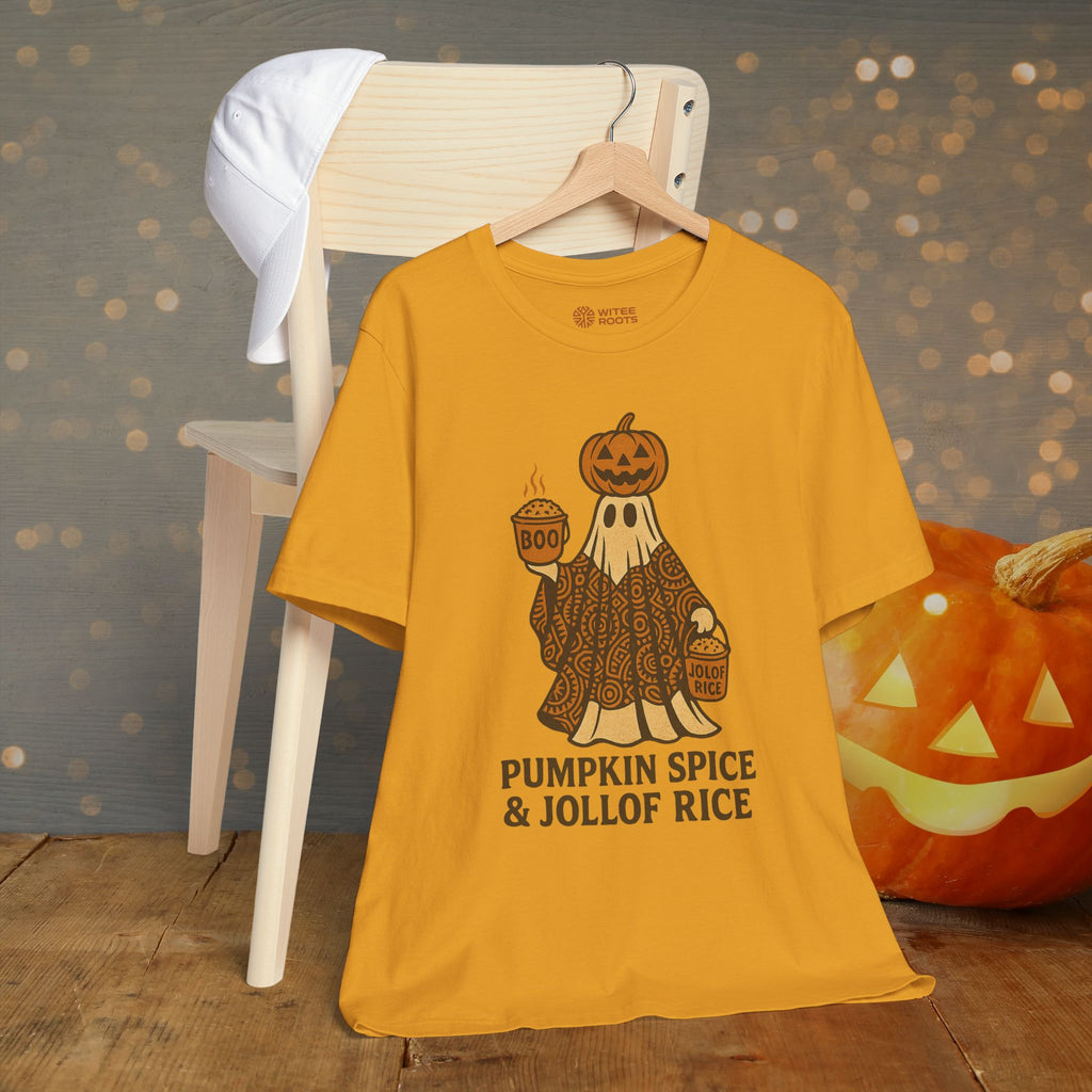 A mustard yellow graphic t-shirt hanging on a wooden hanger, styled on a white wooden chair next to a carved jack-o'-lantern pumpkin against a sparkly gray background.