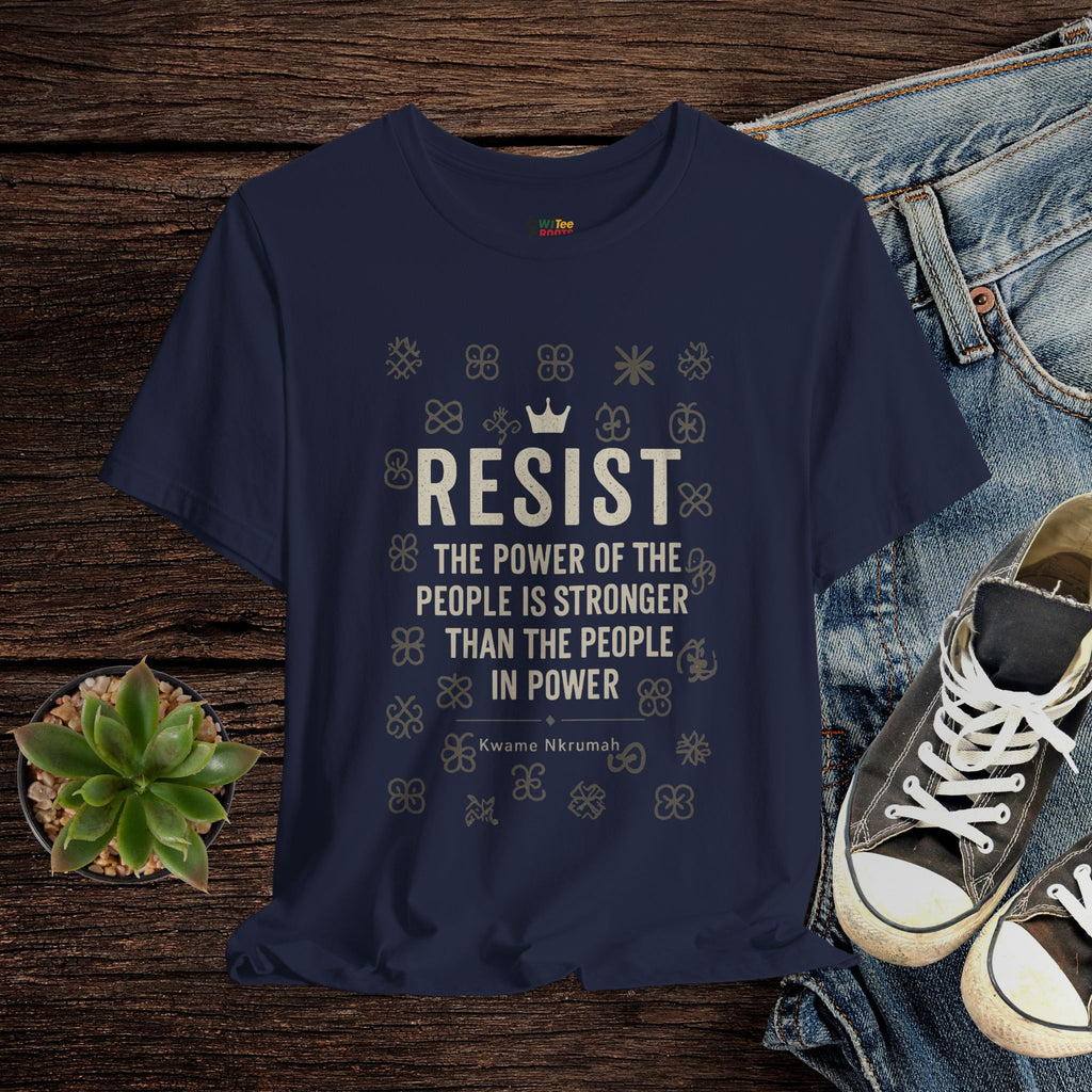 Navy blue t-shirt with 'RESIST' text on a wooden surface with jeans and sneakers.