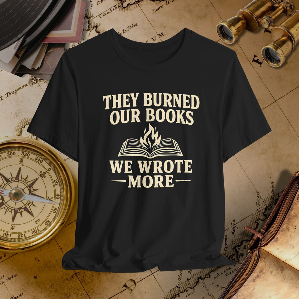 Black t-shirt with 'They burned our books, we wrote more' text on a vintage background with books and binoculars.