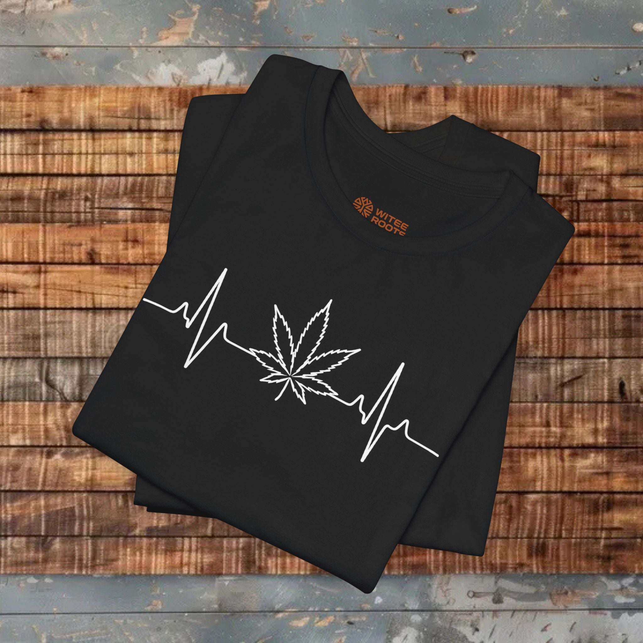 Black t-shirt with white cannabis leaf and heartbeat line design on a wooden surface