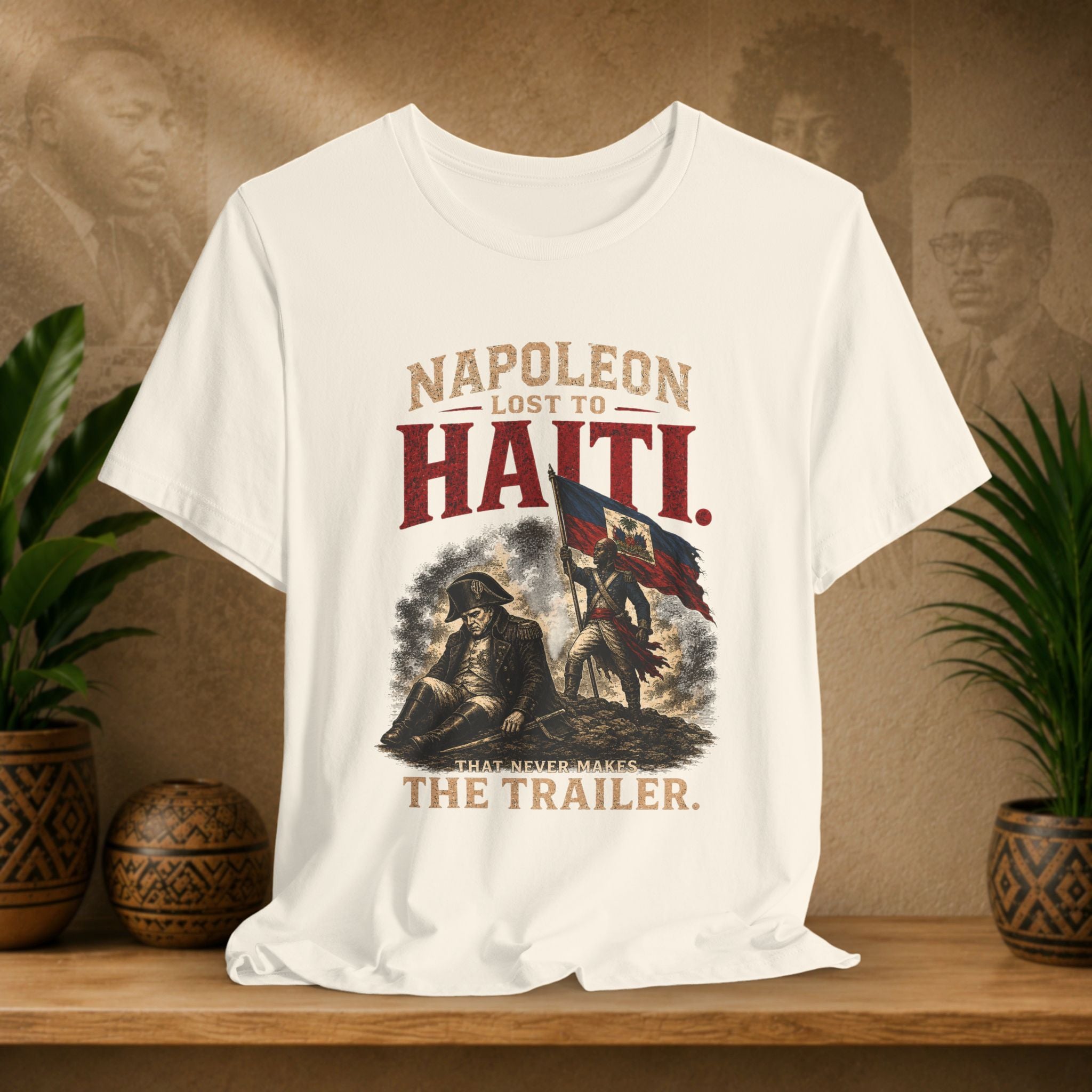 Beige t-shirt with graphic design and text on a wooden surface with plants and a textured wall background