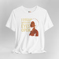White t-shirt with a graphic of a woman and text 'I Dream With My Eyes Open' on a gray background