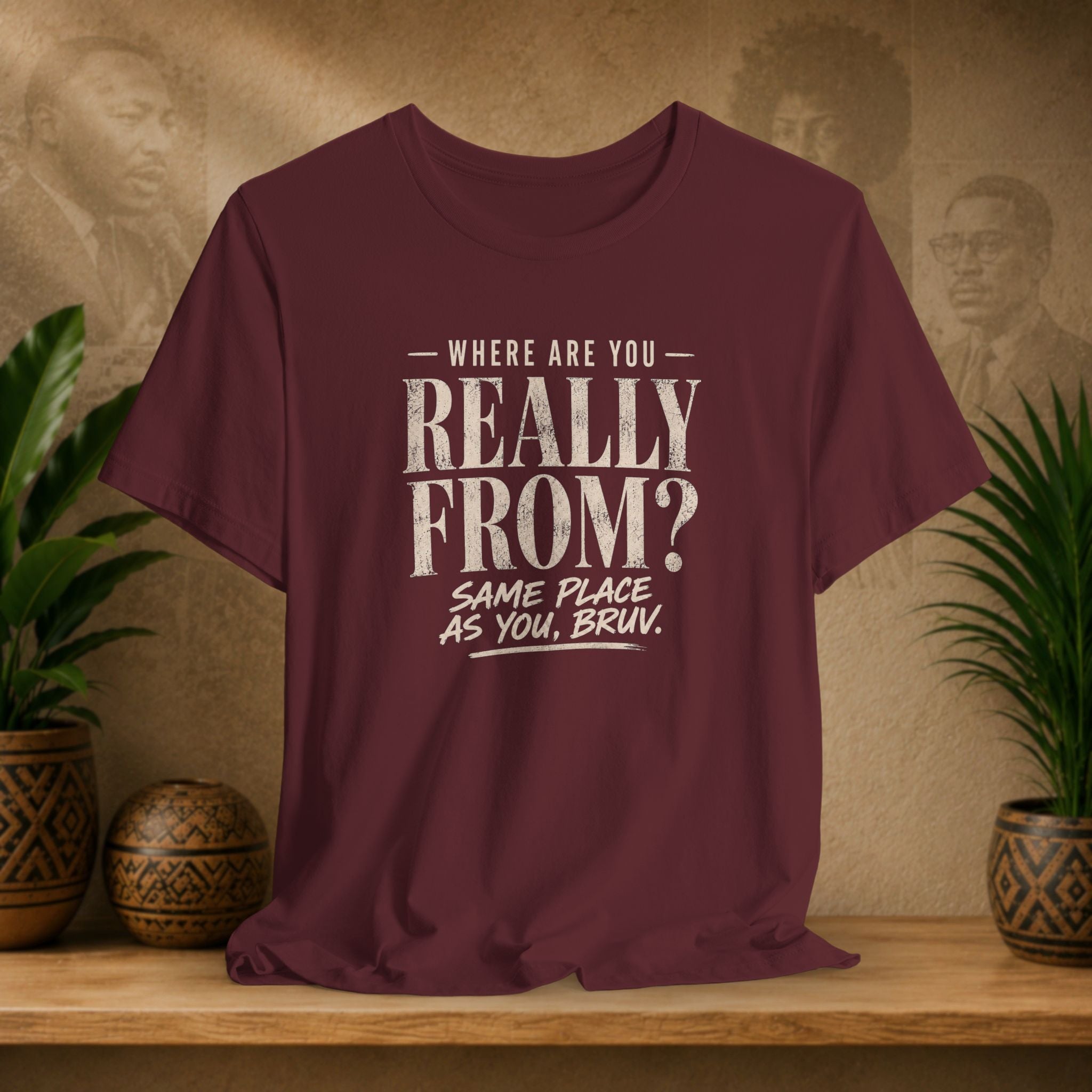 Maroon t-shirt with humorous text design on a wooden surface with plants and decorative items.