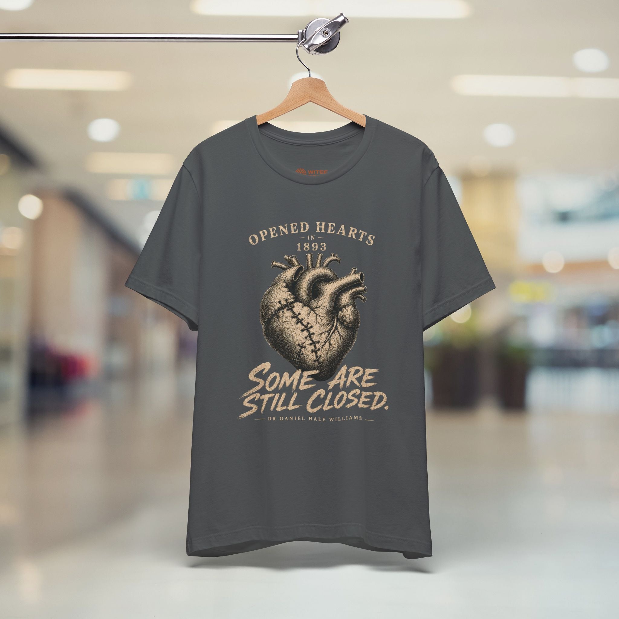 Gray t-shirt with a graphic design on a hanger in a store setting