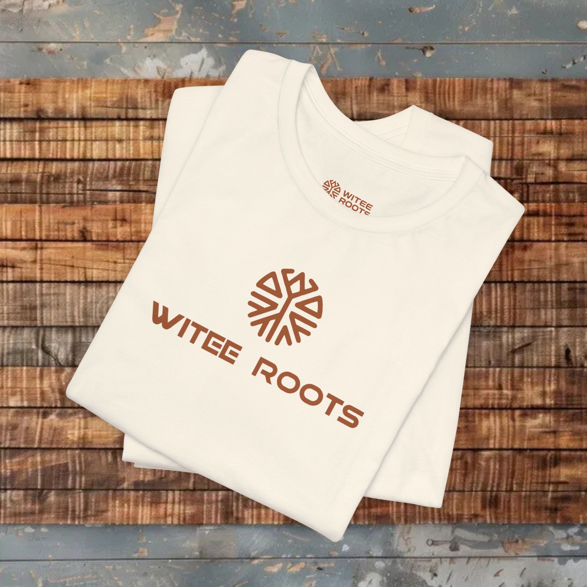 White t-shirt with 'WITEE ROOTS' logo on a wooden surface