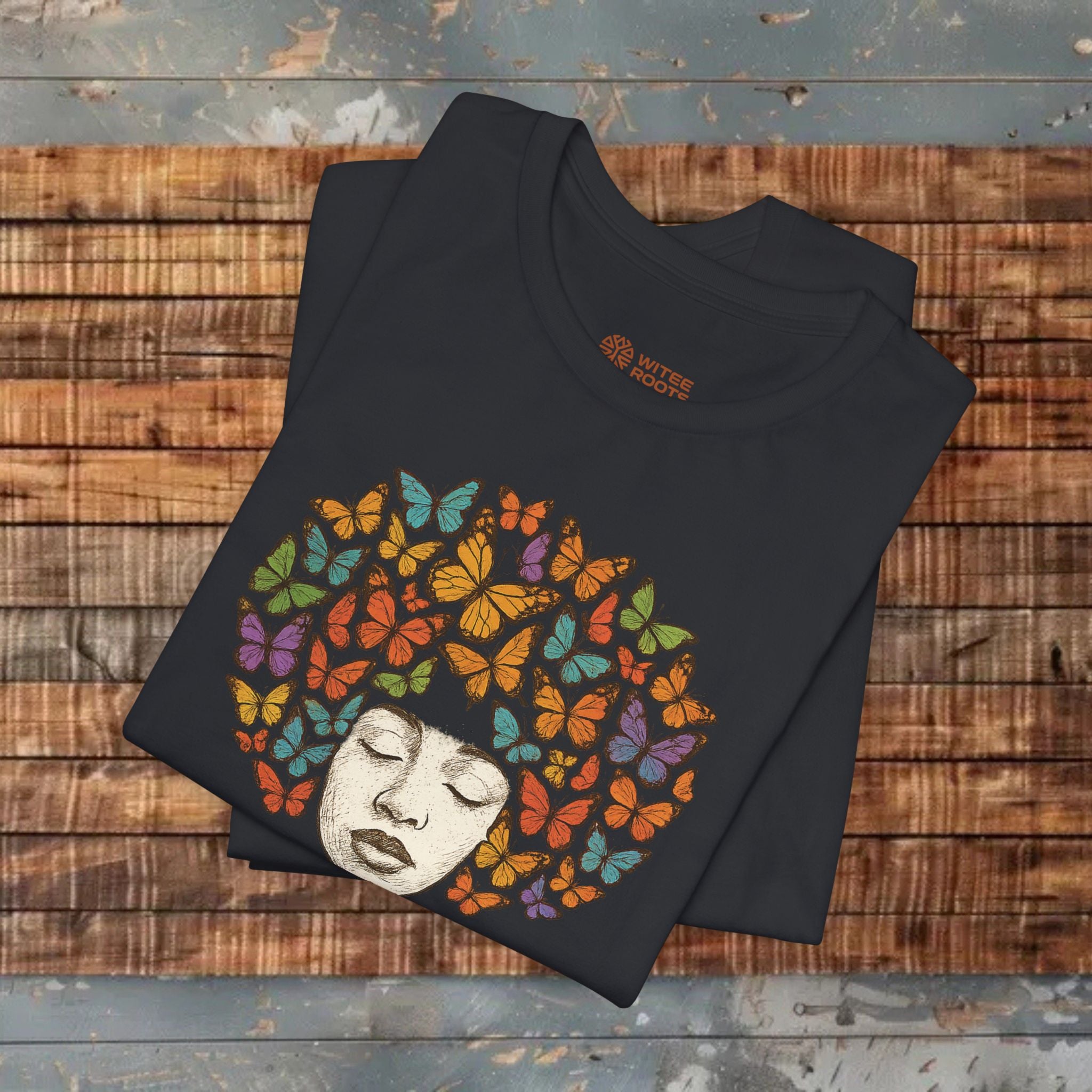 Black t-shirt with colorful butterfly design on a wooden surface