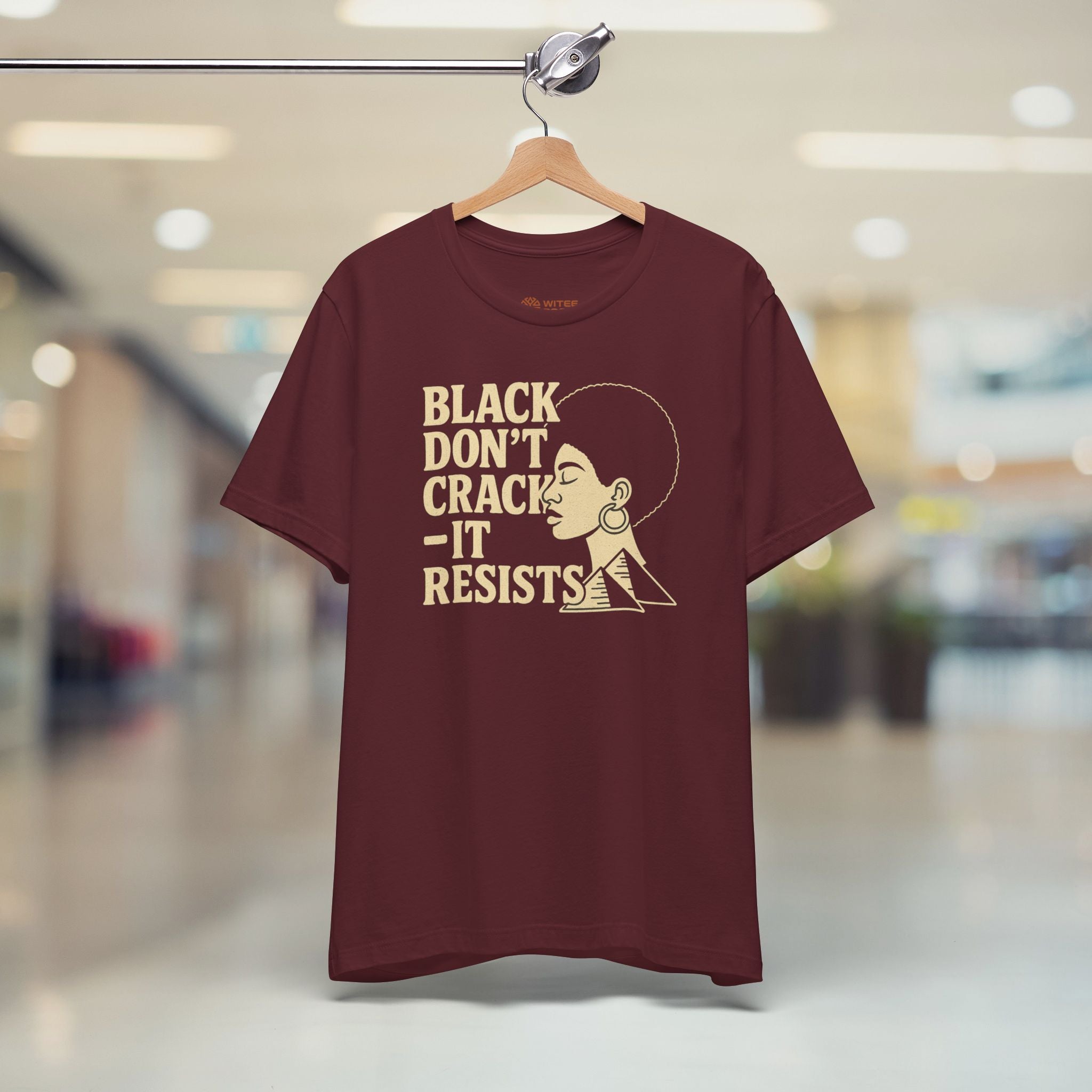 Maroon t-shirt with graphic design and text on a hanger in a store setting