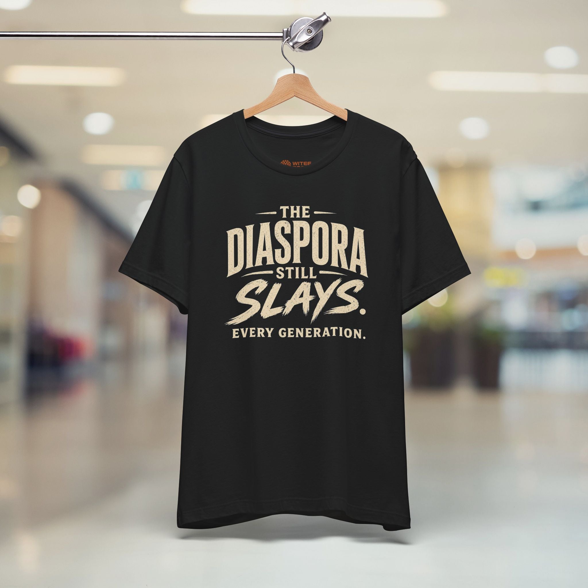 Black t-shirt with 'The Diaspora Still Slays Every Generation' text on a hanger.