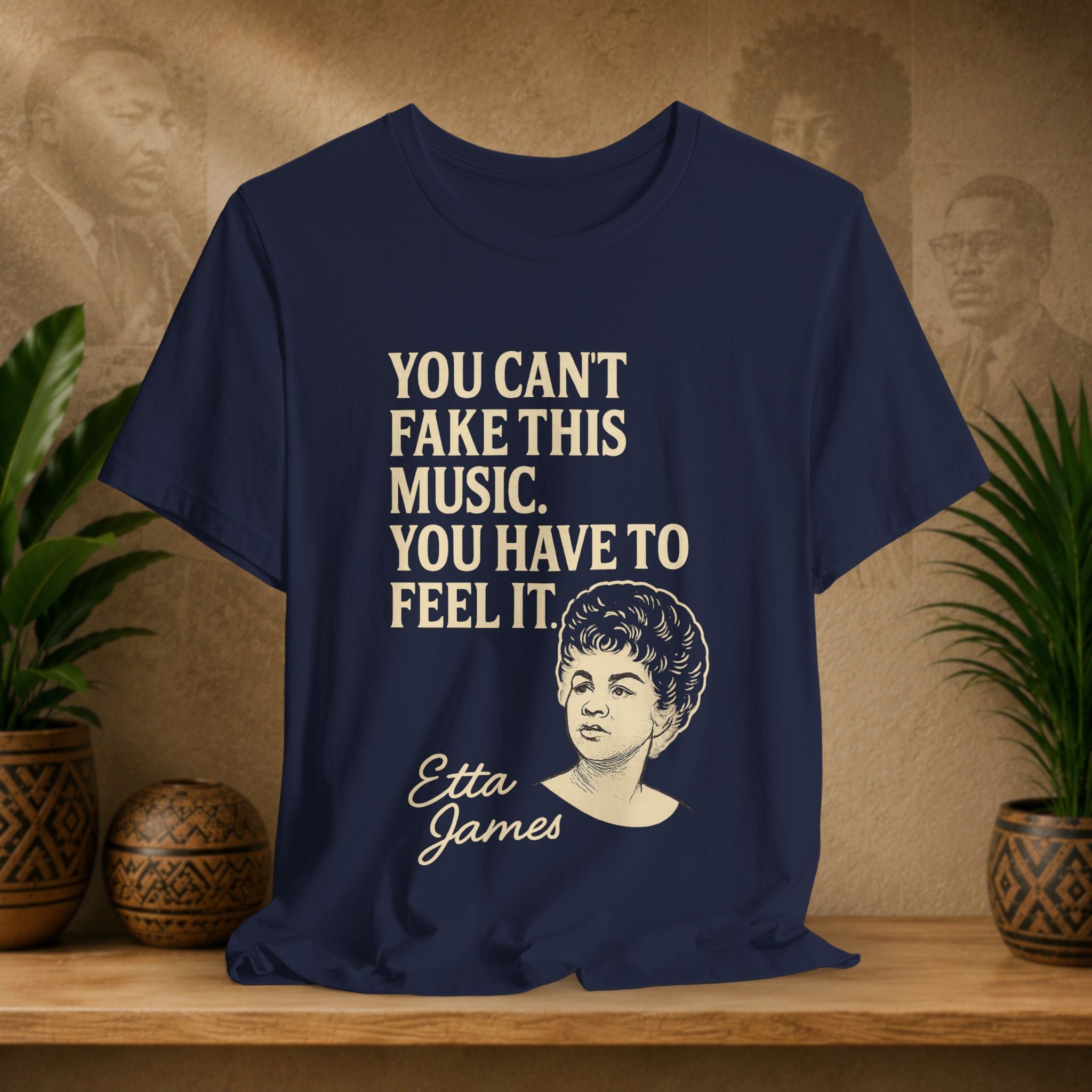 Navy blue t-shirt with Etta James quote on a wooden surface with plants and a vintage-style portrait in the background.