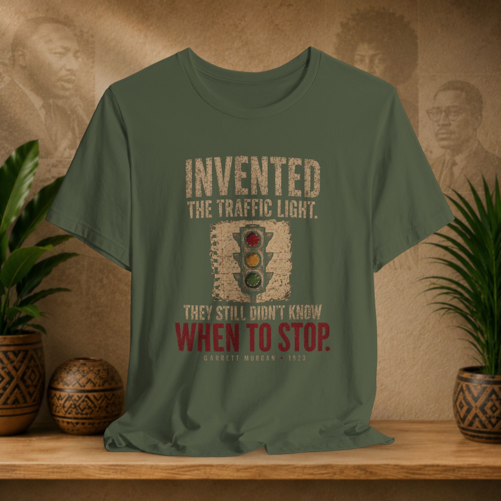 Green t-shirt with traffic light graphic and text on a wooden surface with plants and wall art.