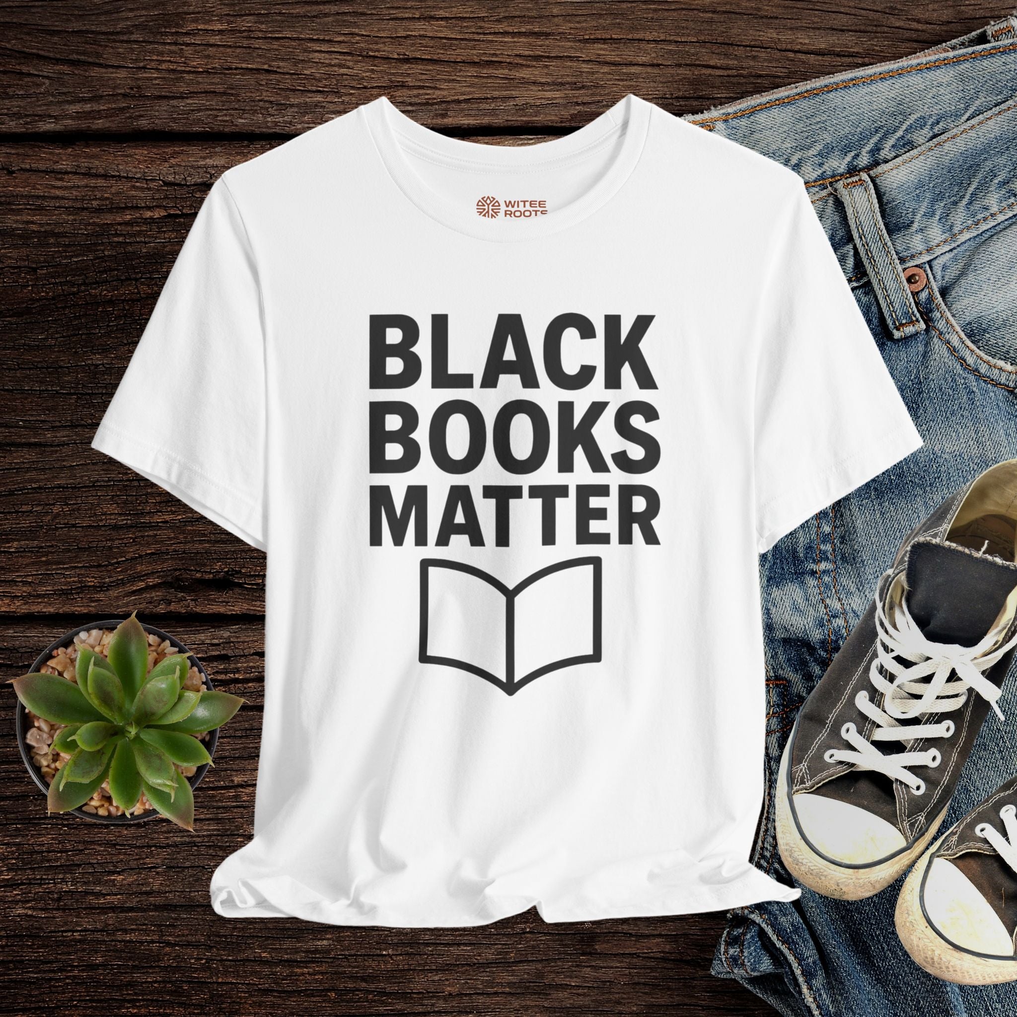 White t-shirt with 'Black Books Matter' text on a wooden surface with jeans and sneakers.