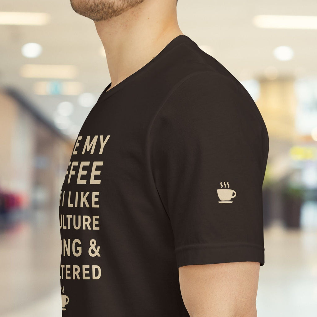 Person wearing a black t-shirt with text and a coffee cup icon in a blurred indoor setting