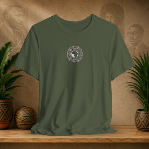 Green t-shirt with a circular design on a wooden surface with plants and decorative items.