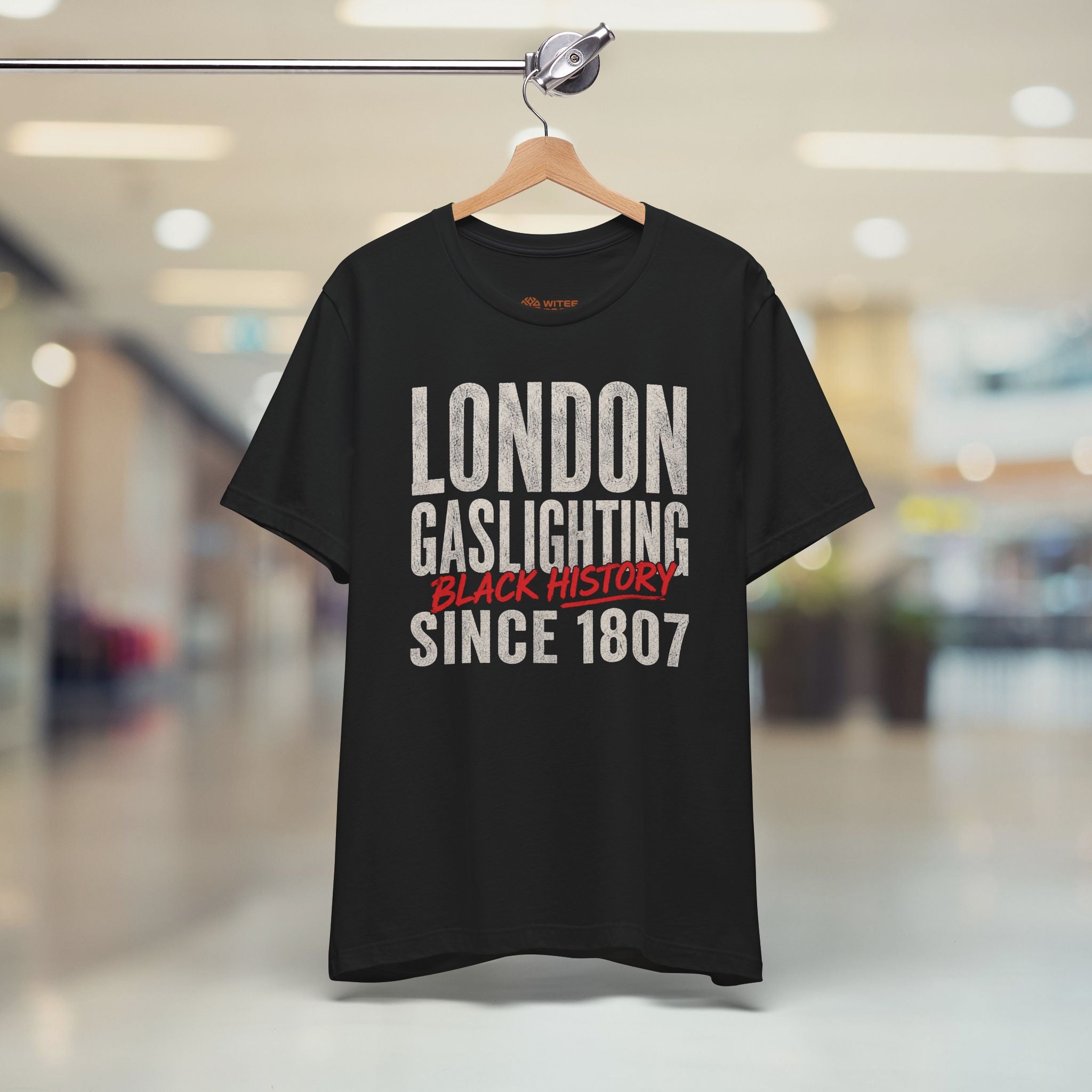 Navy blue t-shirt with humorous text design on a hanger in a mall setting