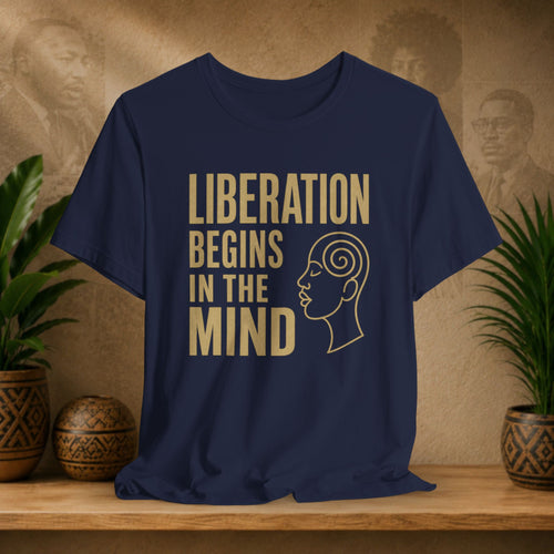 Navy blue t-shirt with 'Liberation Begins in the Mind' text and a profile graphic on a wooden surface with decorative items.