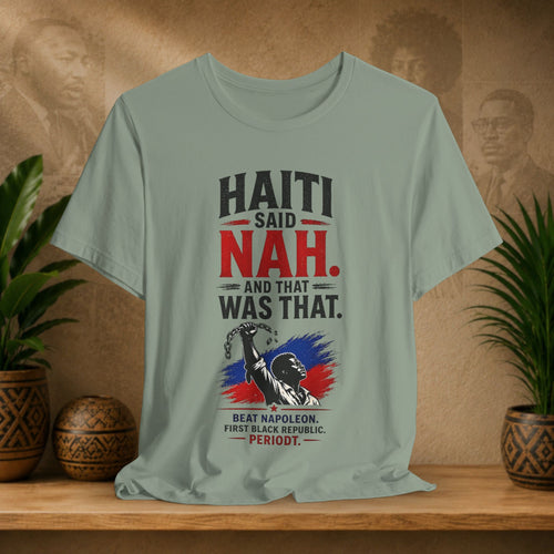T-shirt with 'Haiti Said Nah' design on a wooden shelf with plants and a textured wall background