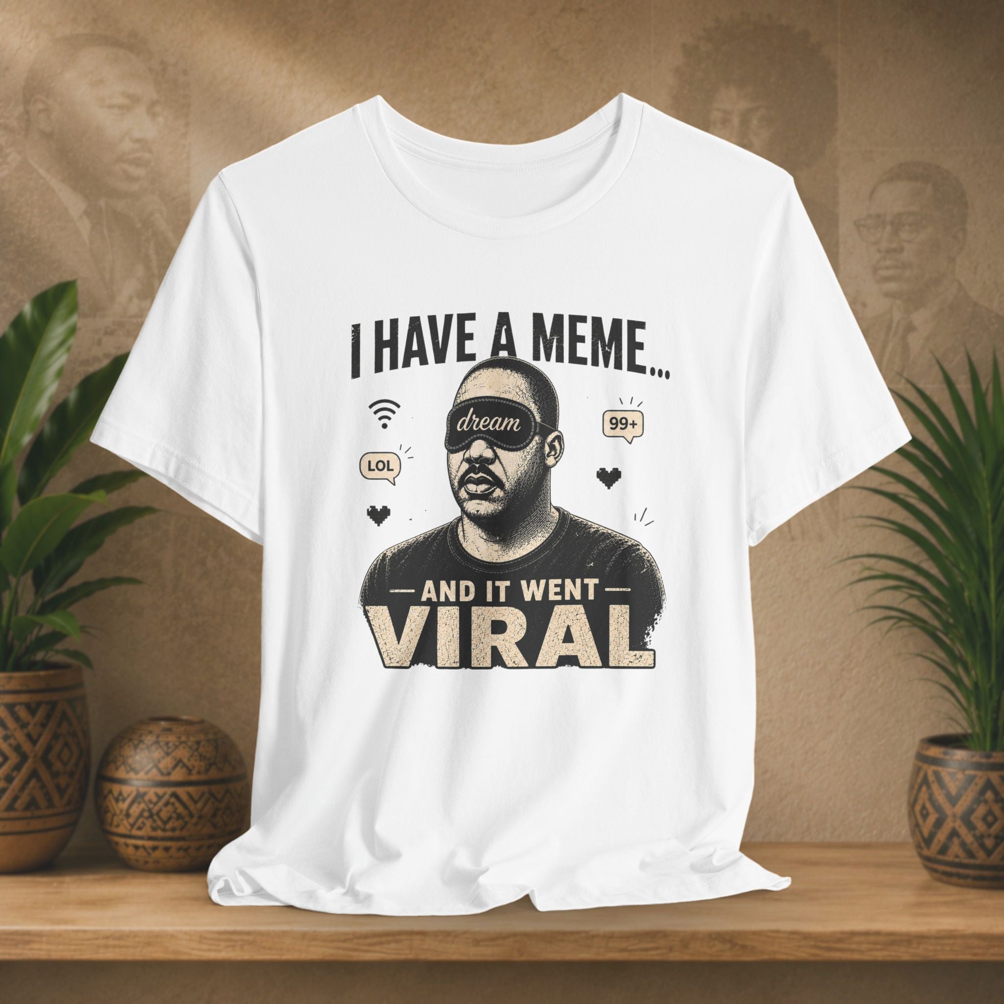 White t-shirt with graphic design and text on a wooden surface with plants and a brown background