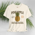 Cream t-shirt with pineapple graphic and text on a light gray background with green leaves.