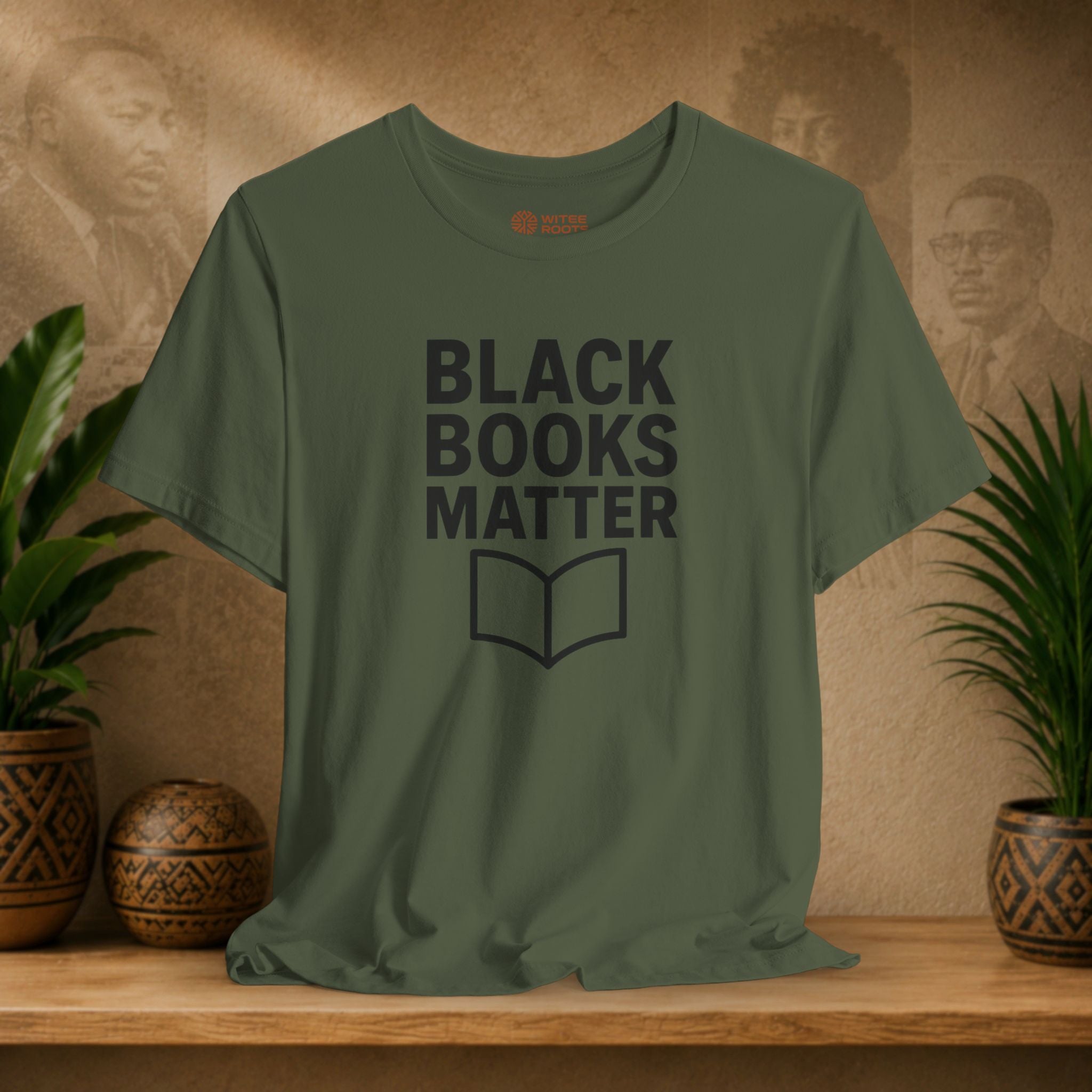 Green t-shirt with 'Black Books Matter' text on a wooden surface with decorative items.