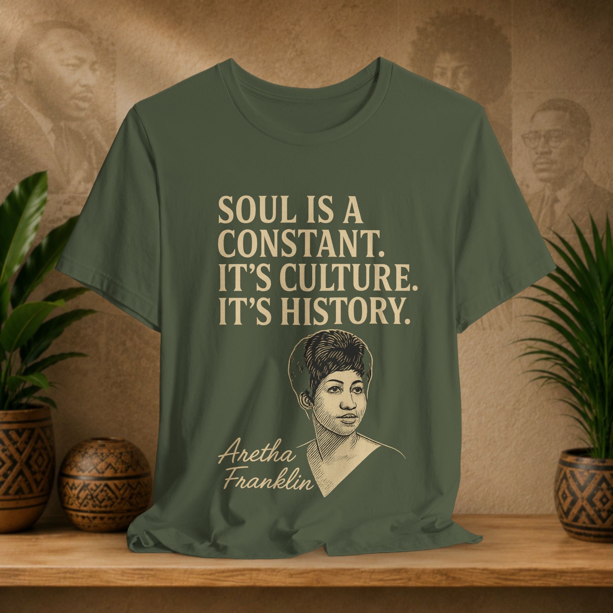 Green t-shirt with Aretha Franklin quote on a wooden surface with plants and wall art in the background