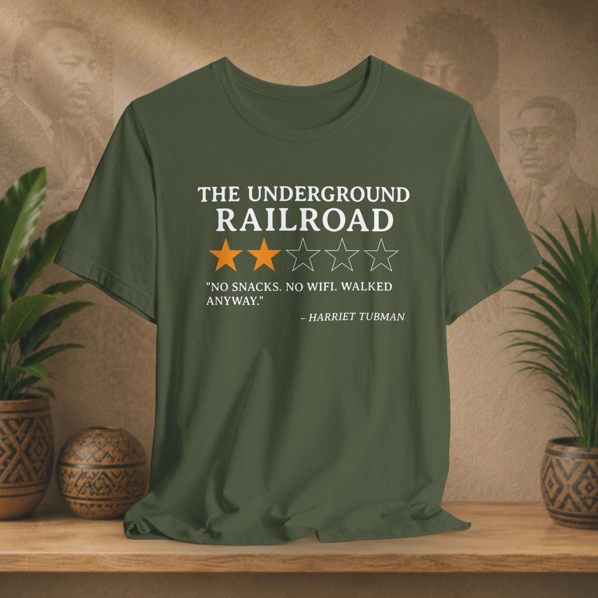 Green t-shirt with text and stars on a wooden surface with plants and a textured wall background