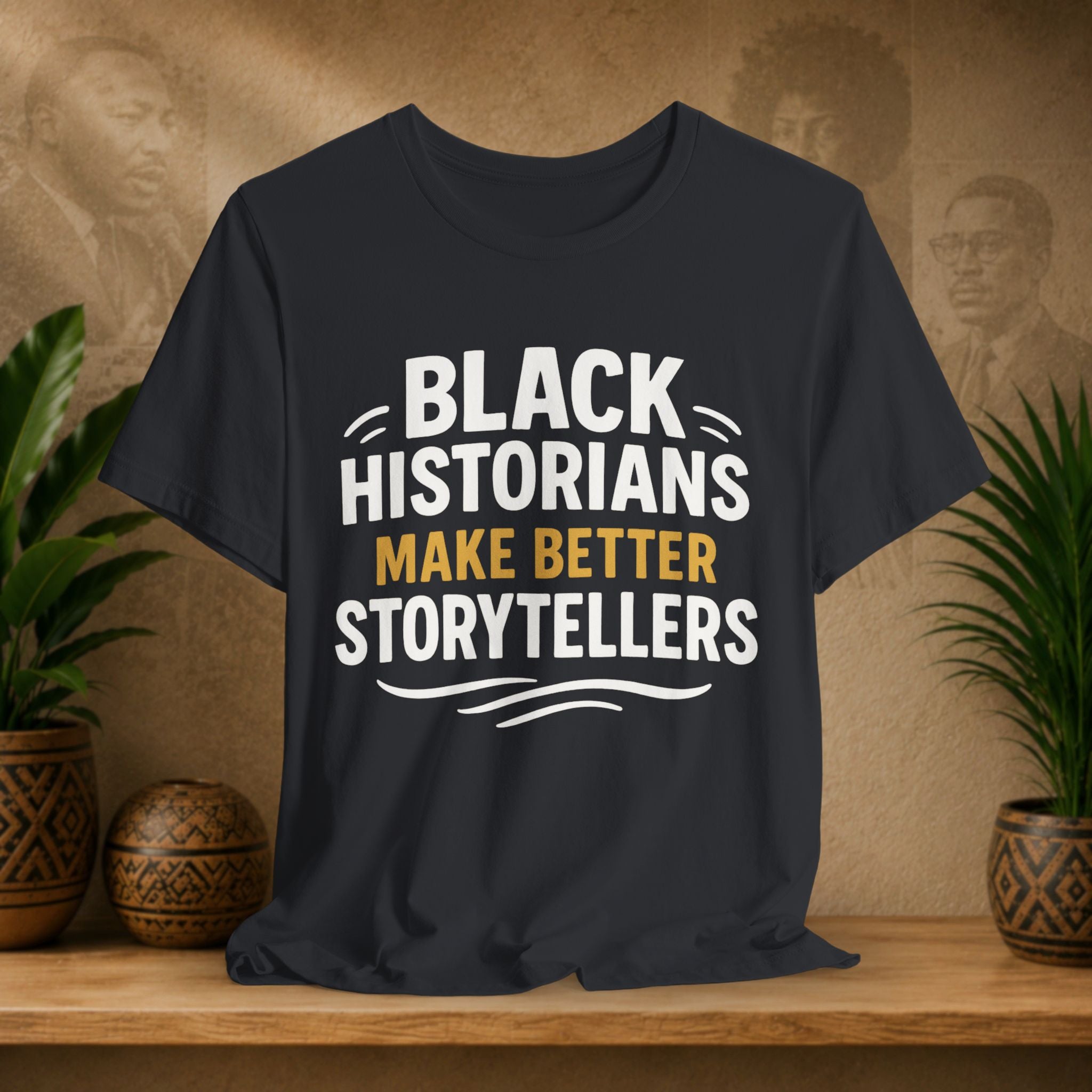 Black t-shirt with 'Black Historians Make Better Storytellers' text on a wooden surface with plants and decorative items.