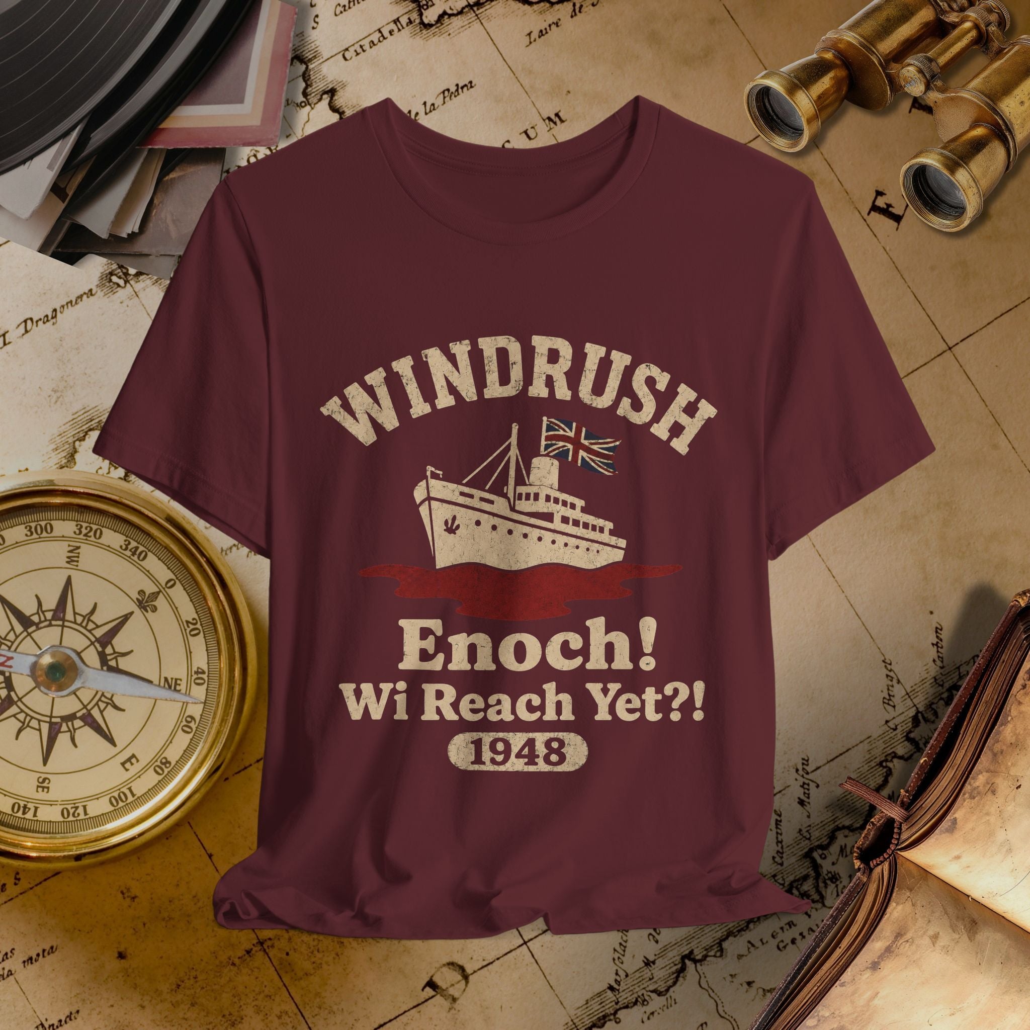 Maroon t-shirt with 'Windrush Enoch! Wi Reach Yet?! 1948' design on a vintage map background.