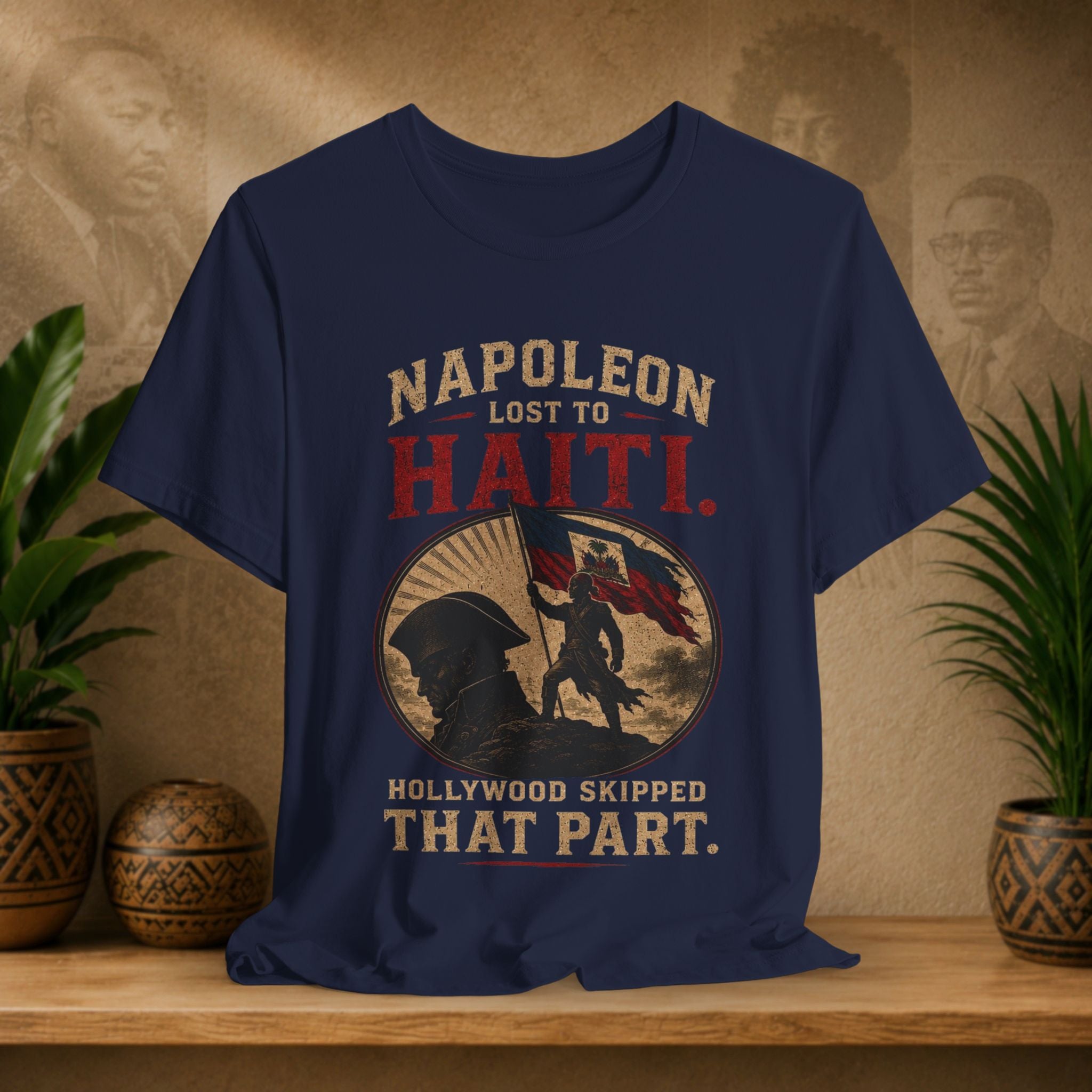 Navy blue t-shirt with graphic design and text on a wooden surface with plants and decorative items.