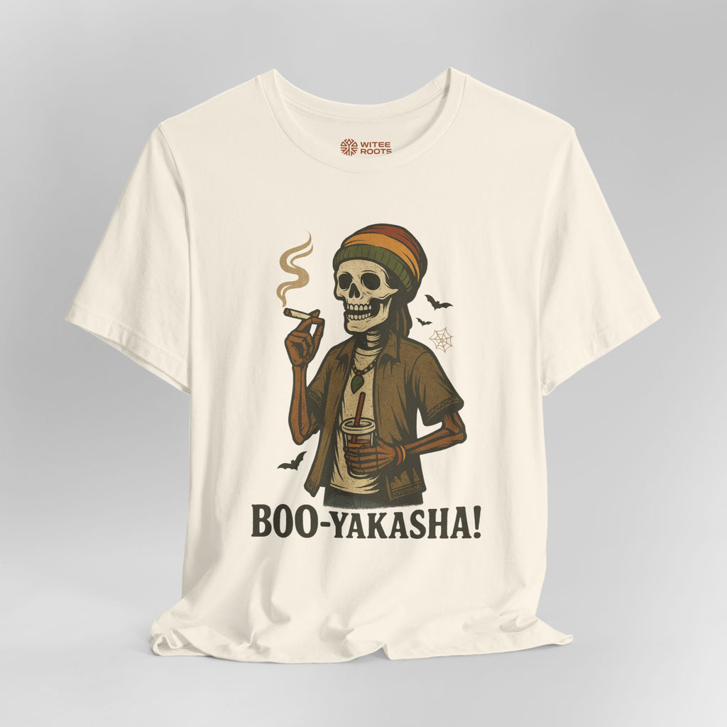 An off-white short-sleeve t-shirt with a graphic of a skeleton wearing a Rasta hat and holding a cigar and a drink, with the text 'BOO-YAKASHA!' printed below. The shirt is shown on a neutral gray background.