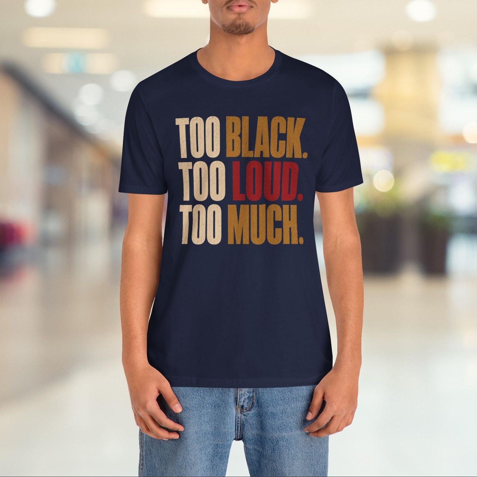 A man wearing a navy blue graphic t-shirt with the text 'TOO BLACK. TOO LOUD.