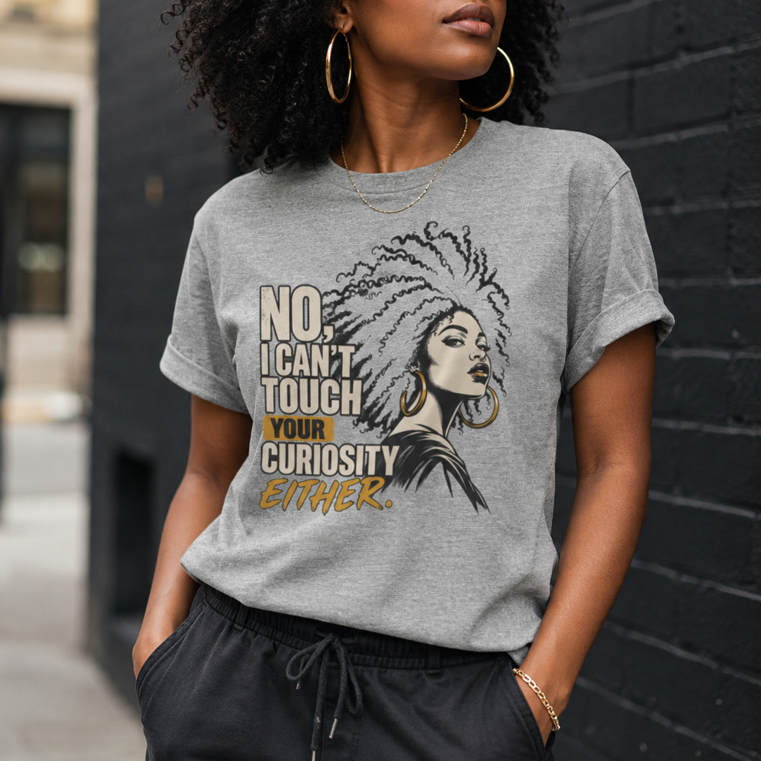 A woman wearing a heather gray graphic t-shirt with a black and gold design that reads 'NO. I CAN'T TOUCH YOUR CURIOSITY EITHER.