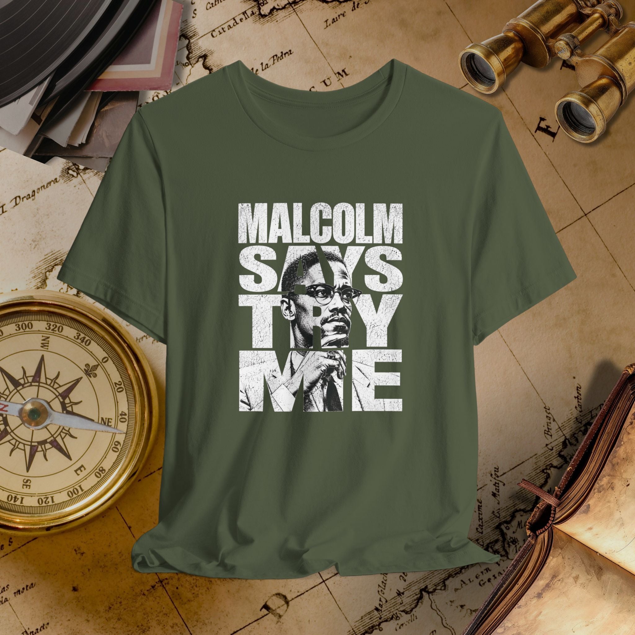 Green t-shirt with 'Malcolm Says Thy Me' graphic on a vintage map background