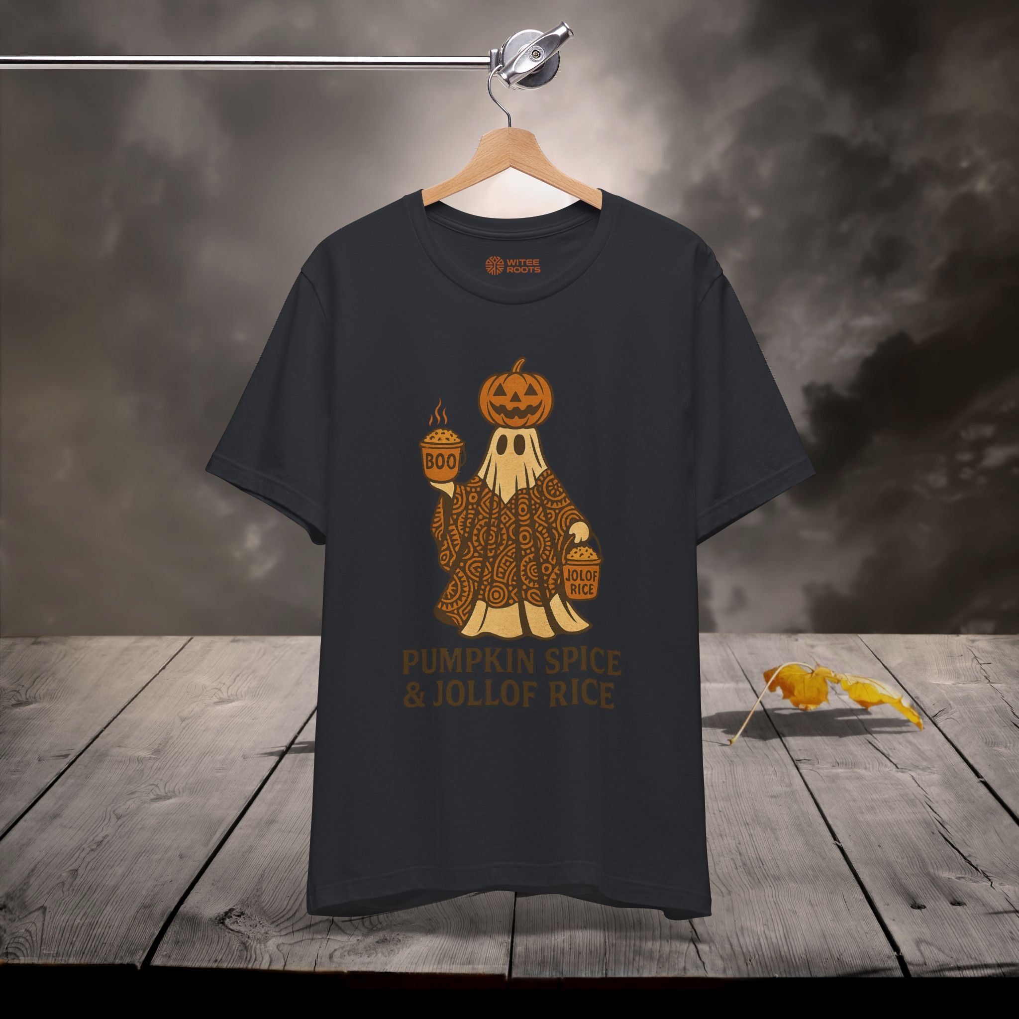 Black t-shirt with pumpkin spice and jollof rice graphic on a wooden surface with dark background