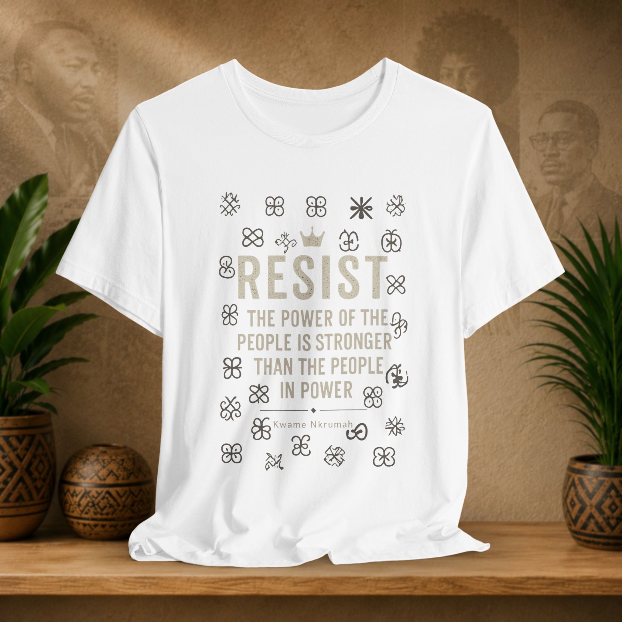 White t-shirt with motivational quote on a wooden surface with plants and a blurred background