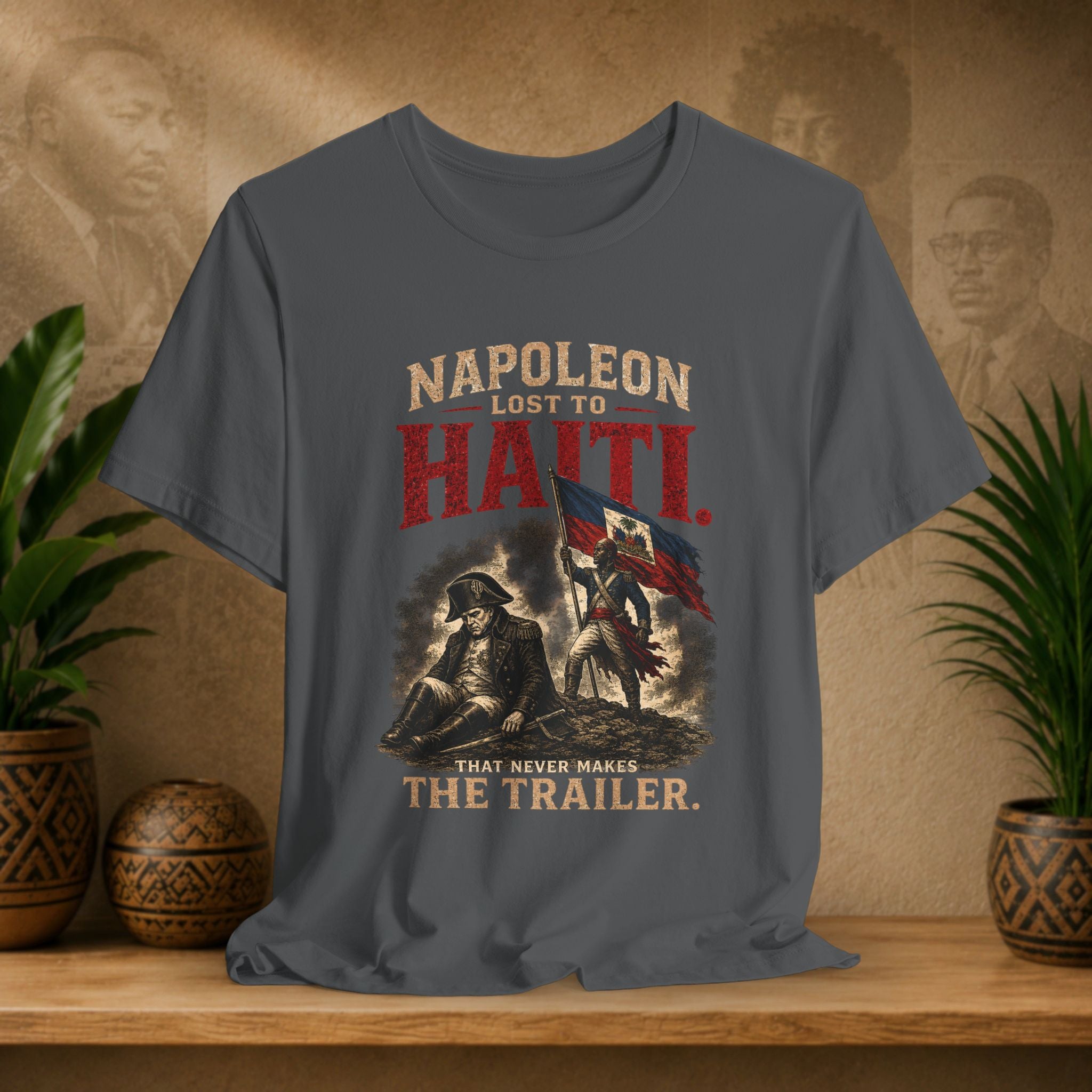 Gray t-shirt with historical graphic and text on a wooden surface with plants and decorative items.